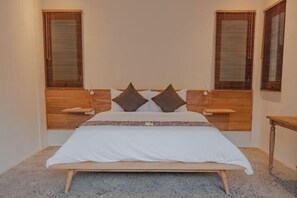 Een slaapkamer met een houten hoofdbord, een witte spreideken, twee kussens en houten nachtkastjes.