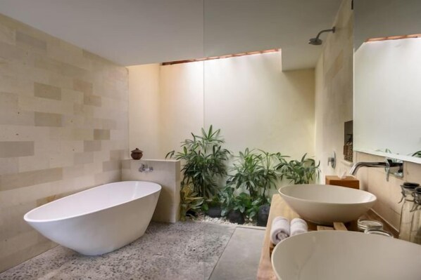 A modern bathroom with a freestanding bathtub, a large vessel sink, and a mirror above the sink.