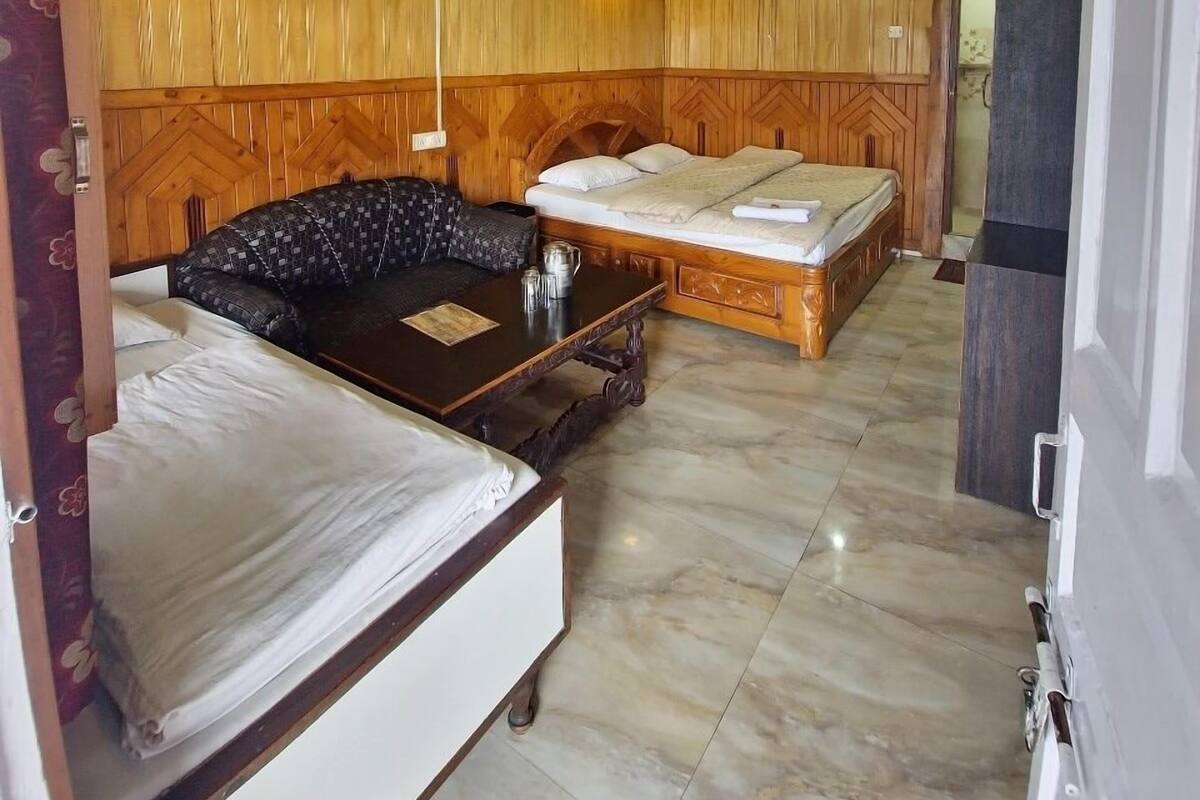 Une petite salle de bain avec un plancher en bois, un lavabo blanc et un banc à motifs.