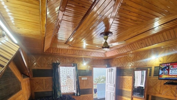 Ein gemütliches Blockhaus-Interieur mit Holzbalkendecke, einem Bett mit Kissen, einem Fenster und einem kleinen Tisch.