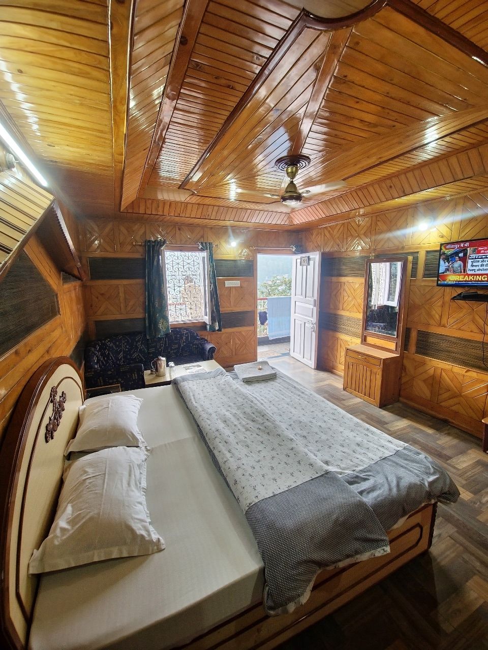 Interior acogedor de una cabaña con techo de madera, una cama con almohadas, una ventana y una pequeña mesa.
