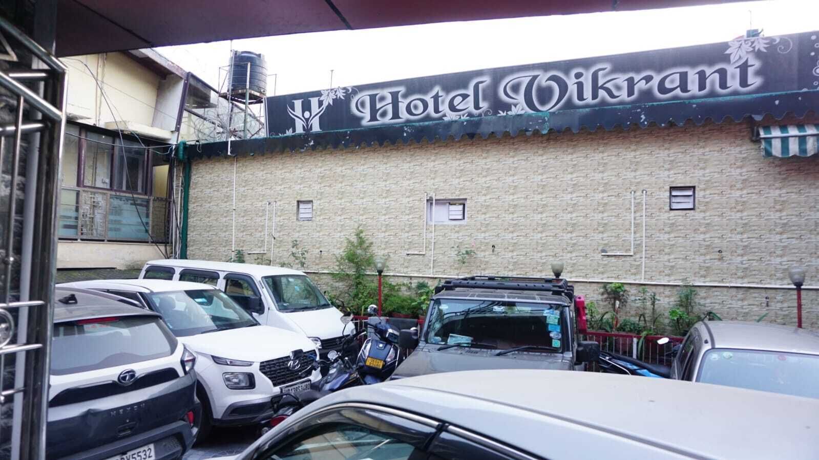 A parking area in front of Hotel Vikrant with several cars parked.