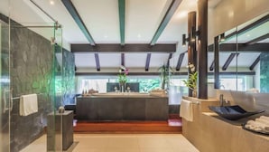 Un baño moderno con pared de piedra, una bañera independiente y un espejo grande.