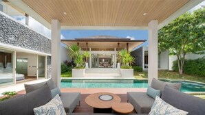 A modern house with a pool, outdoor seating, and a view of the house.