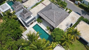 A residential area with multiple houses, a swimming pool, and lush greenery.