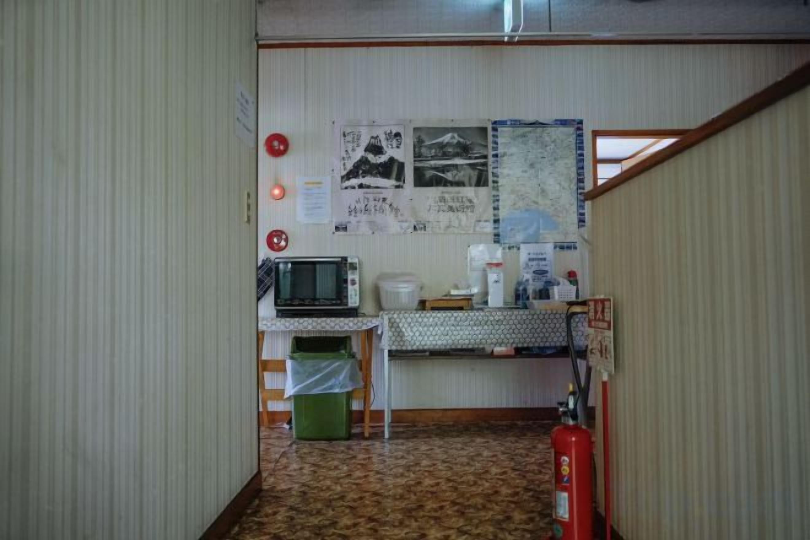 Une petite pièce avec une kitchenette, un four à micro-ondes, une machine à café, un extincteur et une carte accrochée au mur.