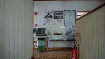 Une petite pièce avec une kitchenette, un four à micro-ondes, une machine à café, un extincteur et une carte accrochée au mur.