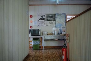 A small room with a kitchenette, a microwave, a coffee maker, a fire extinguisher, and a map on the wall. - FOREST GARDEN HOTEL (Oshino)