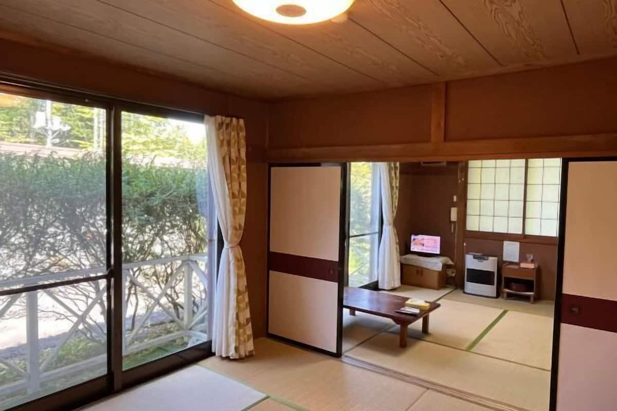 Een traditionele Japanse kamer met tatami vloeren, schuifdeuren, een televisie en een klein tafeltje.