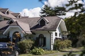 A two-story house with a gabled roof, a front porch, and a visible garage. - FOREST GARDEN HOTEL (Oshino)
