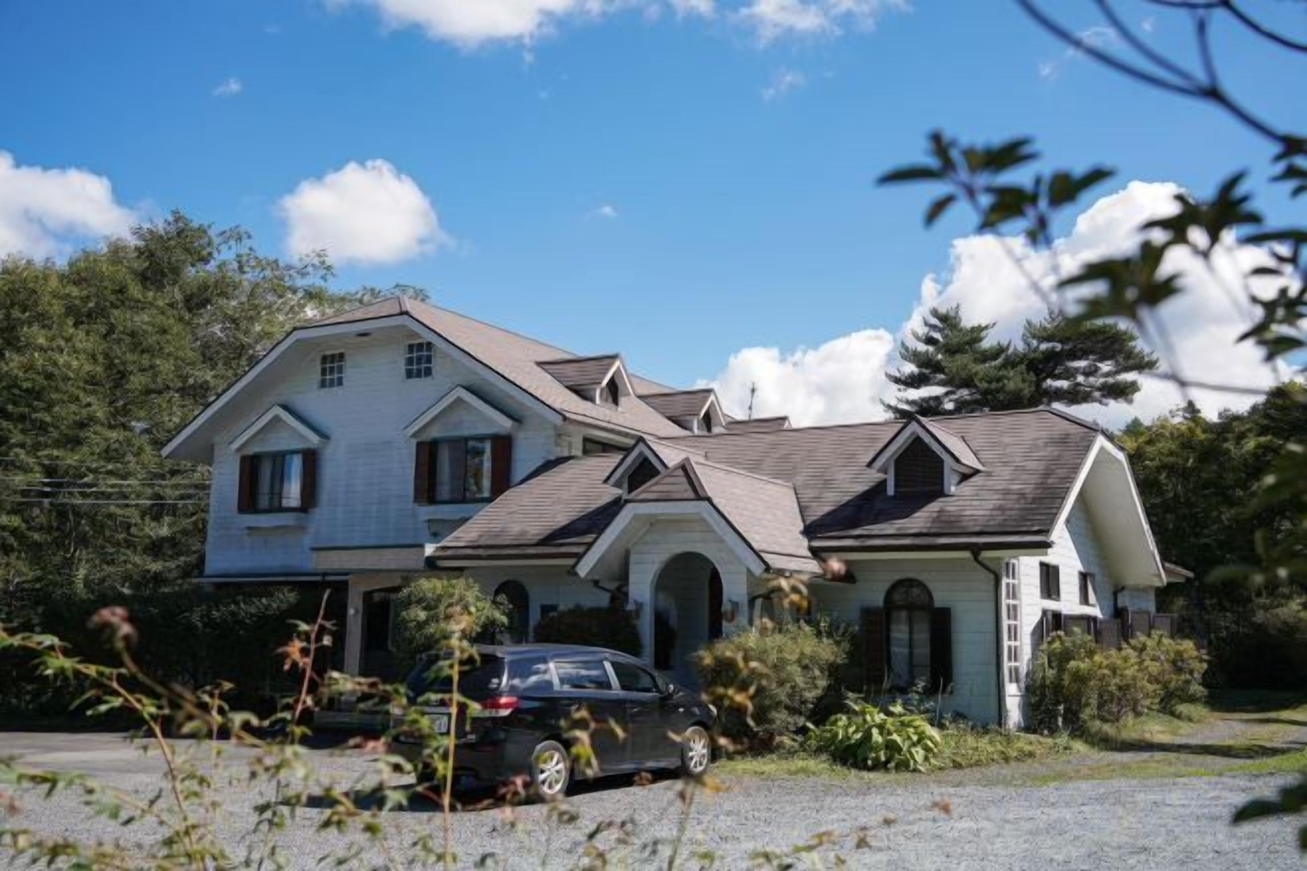 A two-story house with a driveway and a parked car.