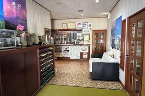 A hotel lobby with a reception desk, a seating area, and a display of amenities. - FOREST GARDEN HOTEL (Oshino)