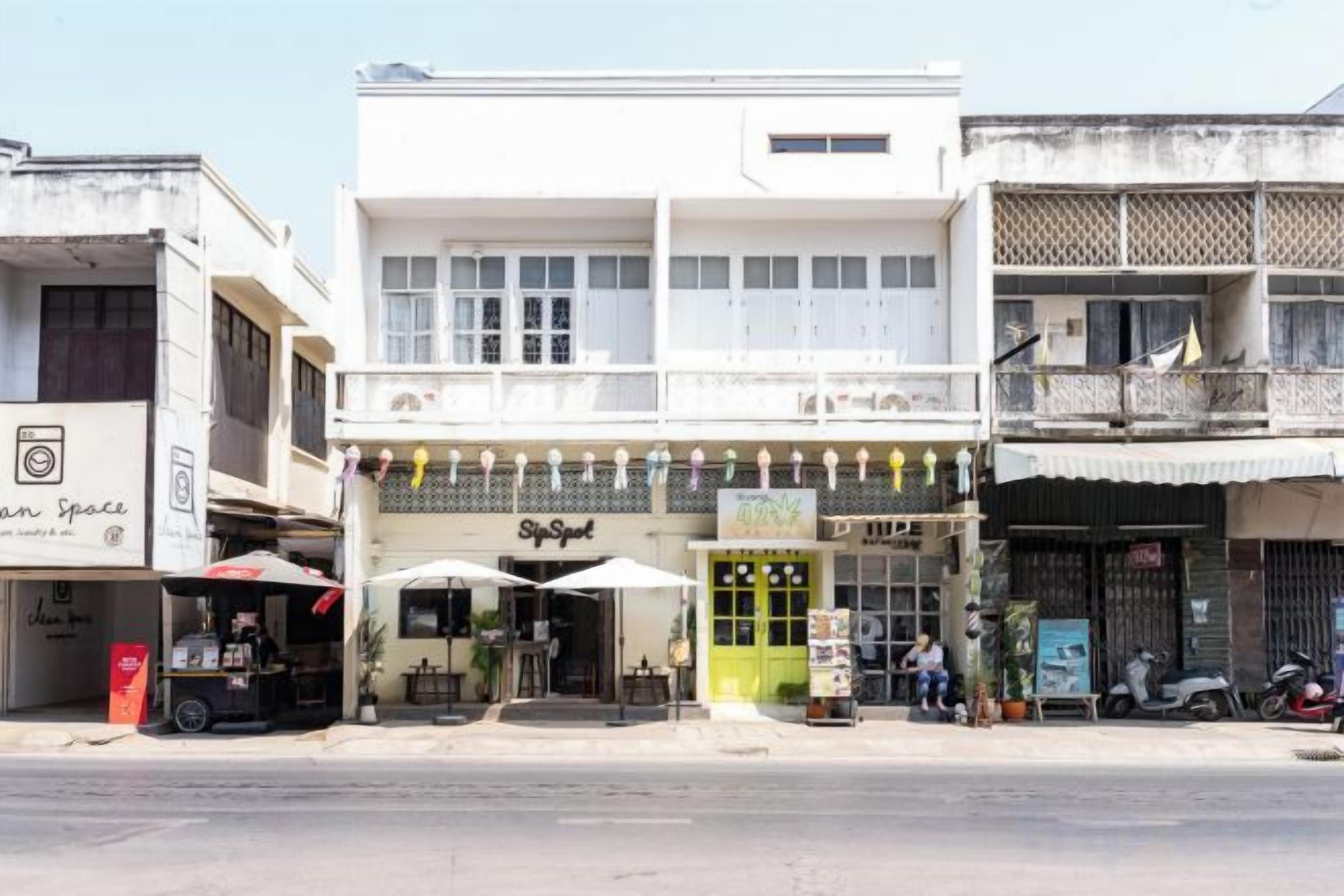 A street view with a two-story building featuring a ground-level shop and upper-level balconies.