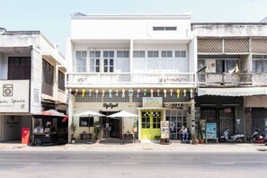 A street view with a two-story building featuring a ground-level shop and upper-level balconies. - Good Moon at Tha Phae (Chiang Mai)