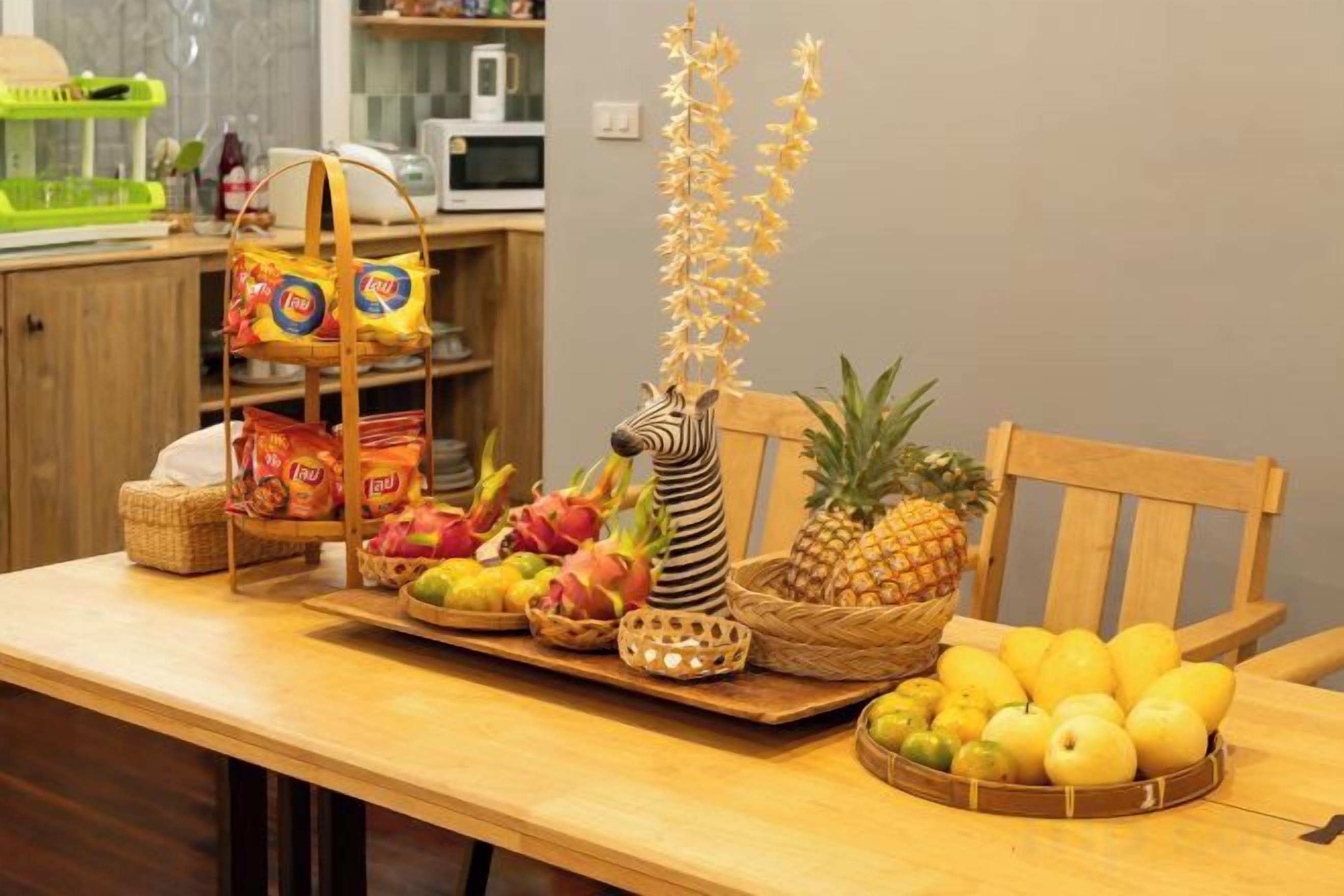 Une table de salle à manger en bois, sur laquelle on trouve divers fruits et en-cas.