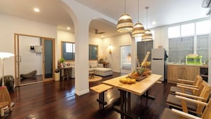 A spacious living area with a wooden dining table, comfortable seating, and pendant lighting. - Good Moon at Tha Phae (Chiang Mai)