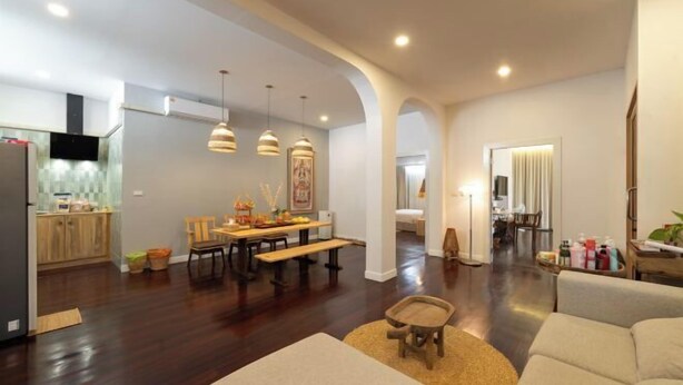 A spacious living area with a dining table, sofas, and a kitchen in the background. - Good Moon at Tha Phae (Chiang Mai)
