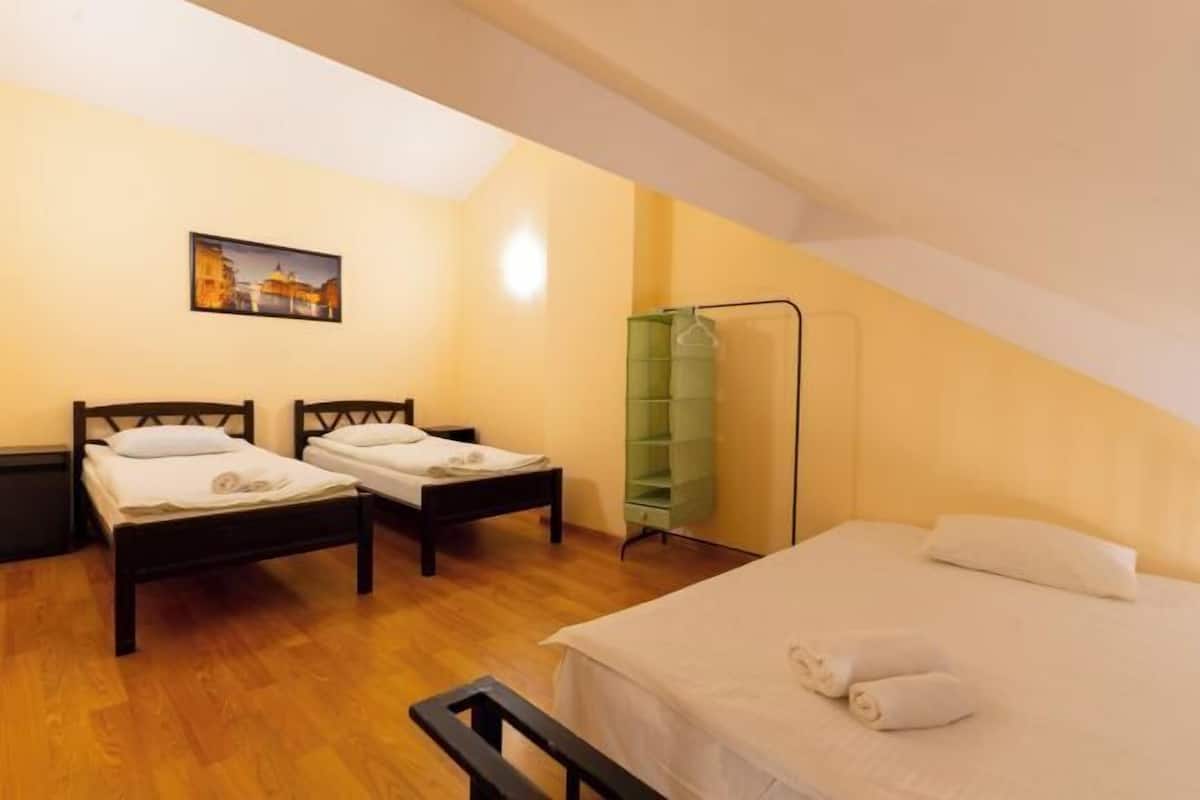 A room with two beds, a green wardrobe, and a painting on the wall.