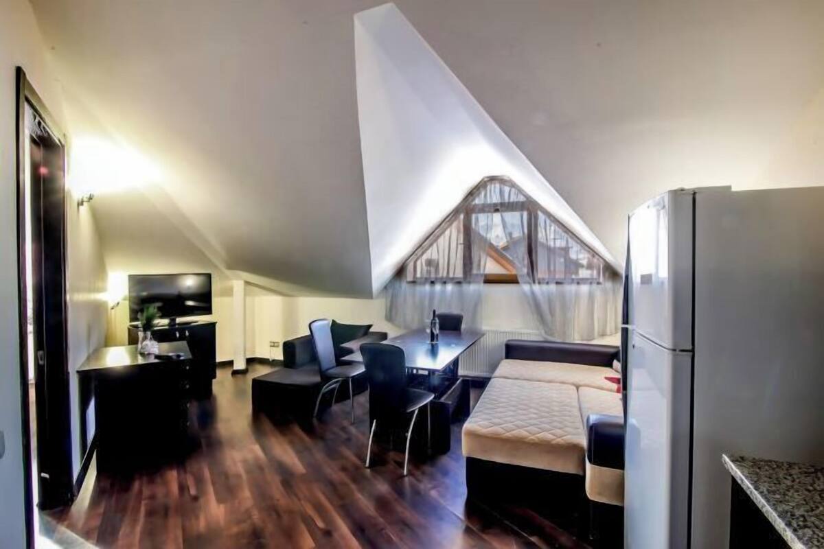 A compact living space with a dining area, kitchenette, and a large window.
