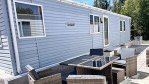 A mobile home with a patio area featuring wicker furniture and a glass table. - Mobile home Seehund at the Geiseltalsee (Mücheln (Geiseltal))