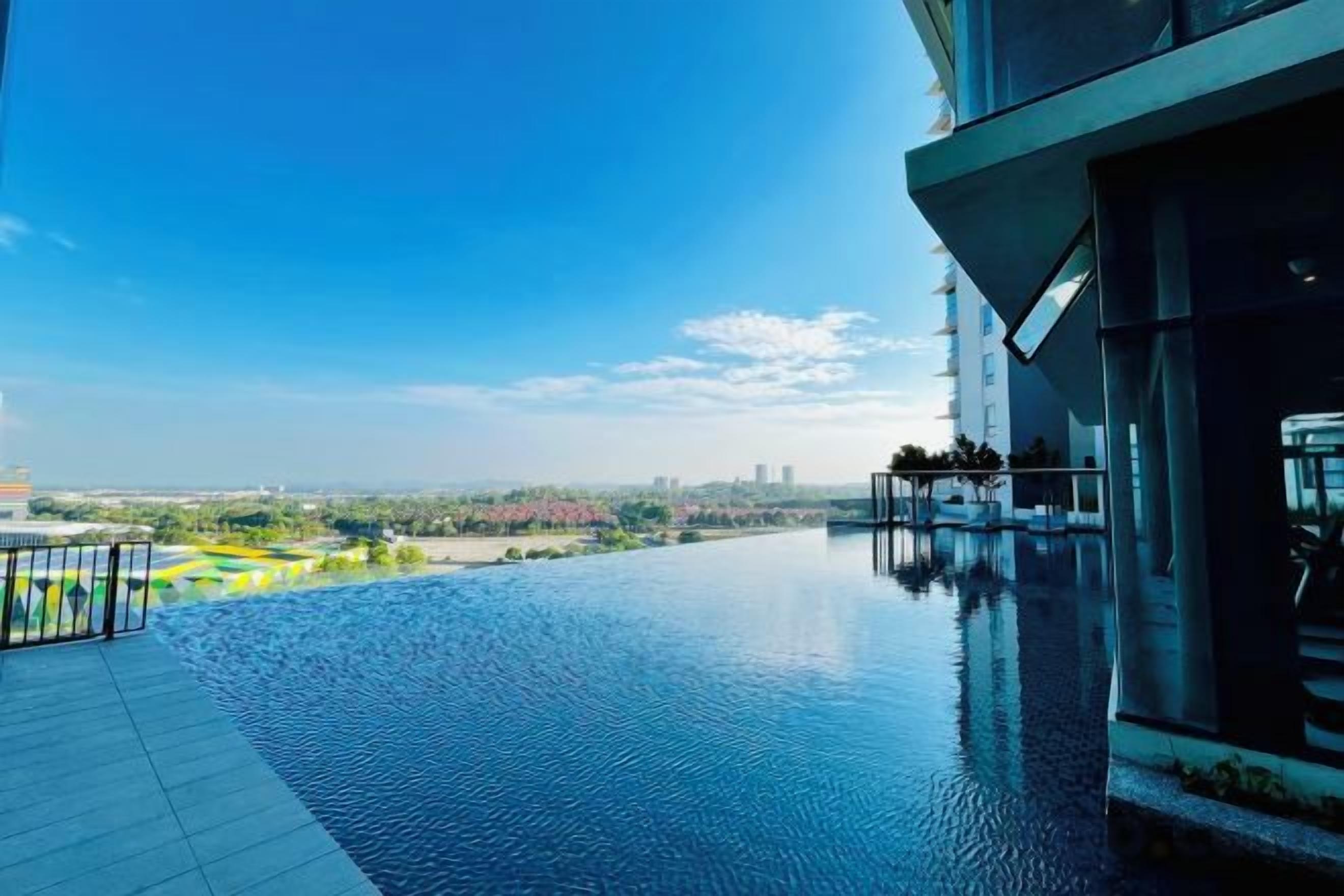A modern building with a rooftop infinity pool overlooking a cityscape.