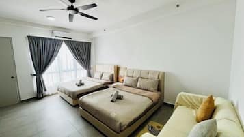 A hotel room with two beds, a ceiling fan, a sofa, and a window with curtains.