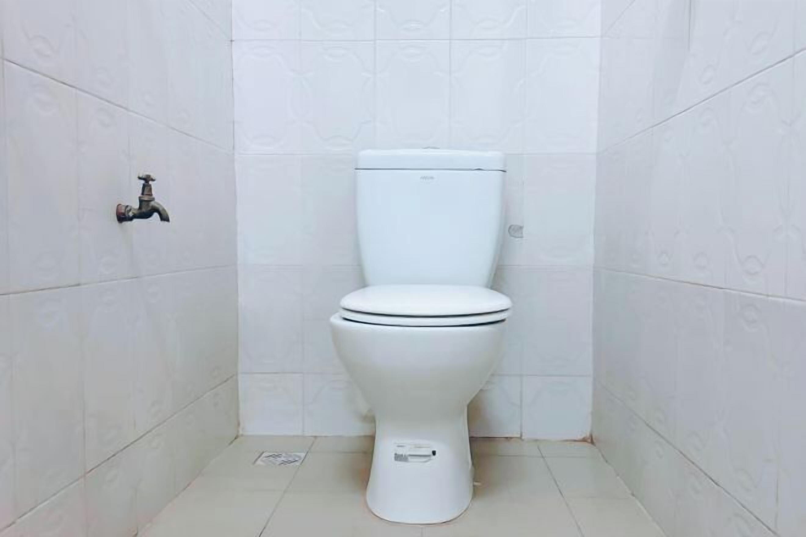 Un water bianco in un bagno con piastrelle bianche a motivi decorativi su pareti e pavimento.