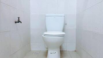 Un water bianco in un bagno con piastrelle bianche a motivi decorativi su pareti e pavimento.