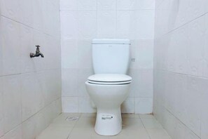Een wit toilet in een badkamer met witte betegelde muren en vloer.