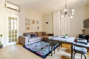A modern living room with a sofa, dining table, and chairs, a ceiling fan, and a TV. - Appartamento Montenero in Porta Romana, Milano Centro (Milan)