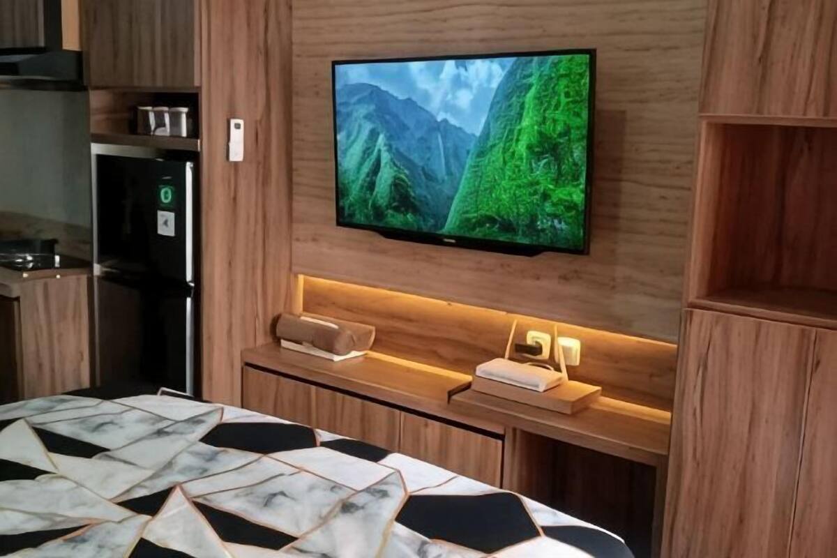Een moderne keuken met een inbouwkoelkast, een flatscreen televisie bevestigd aan een houten wand, en een houten aanrecht met een magnetron.