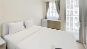 A hotel room with a bed, a desk, a chair, and a window with curtains. - APARTEMEN TRANSPARK JUANDA BEKASI by ilfal (East Bekasi)