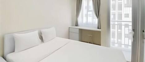 A hotel room with a bed, a desk, a chair, and a window with curtains.