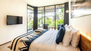 Ein modernes Hotelzimmer mit einem großen Bett, einem Flachbildfernseher und einem Balkon mit Sitzgelegenheit im Freien.