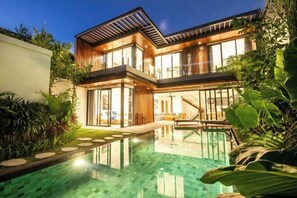 A modern two-story house with a glass-enclosed pool, surrounded by lush greenery. - NOMA 5 VICTUM · (Bali)