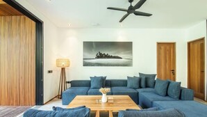 Ein modernes Wohnzimmer mit einem Ecksofa, einem Couchtisch und einem Deckenventilator.
