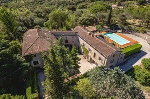 Una villa de piedra con piscina, rodeada de abundante vegetación.