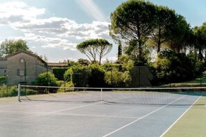 A tennis court with a net, surrounded by trees and a stone building. - Cottage Olive on large domain with Pool, Spa, Tennis (Saint-Julien-les-Rosiers)