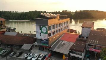 Een meerhoog gebouw met een parkeerplaats ervoor, een rivier op de achtergrond en een boot afgemeerd aan het water.