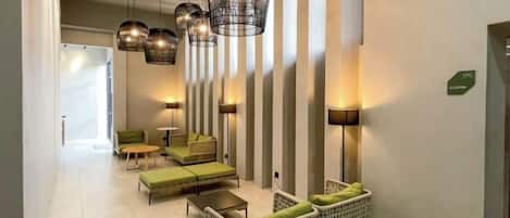 A hotel lobby with seating areas, pendant lighting, and a reception desk.