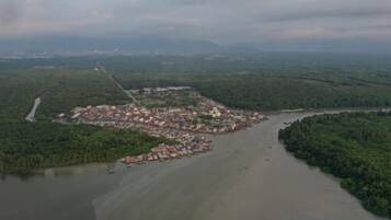 An aerial view of a coastal town with a river, dense greenery, and a mix of residential and commercial buildings.