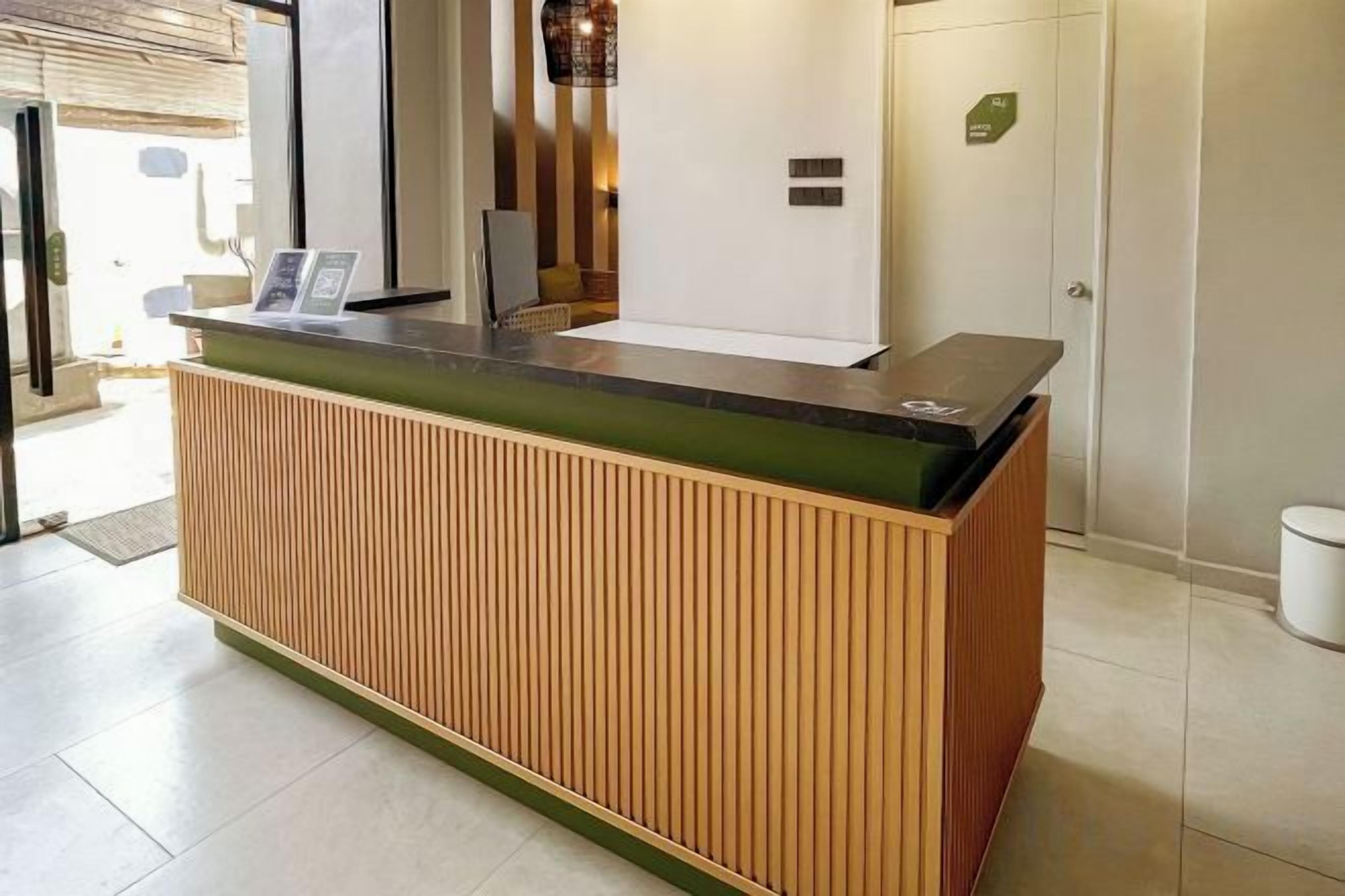 Un mostrador de recepción con paneles de madera, una mampara de vidrio y un pequeño expositor.