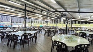 A spacious outdoor dining area with multiple tables and chairs, covered by a metal roof with skylights. - Crosview (Kuala Sepetang)