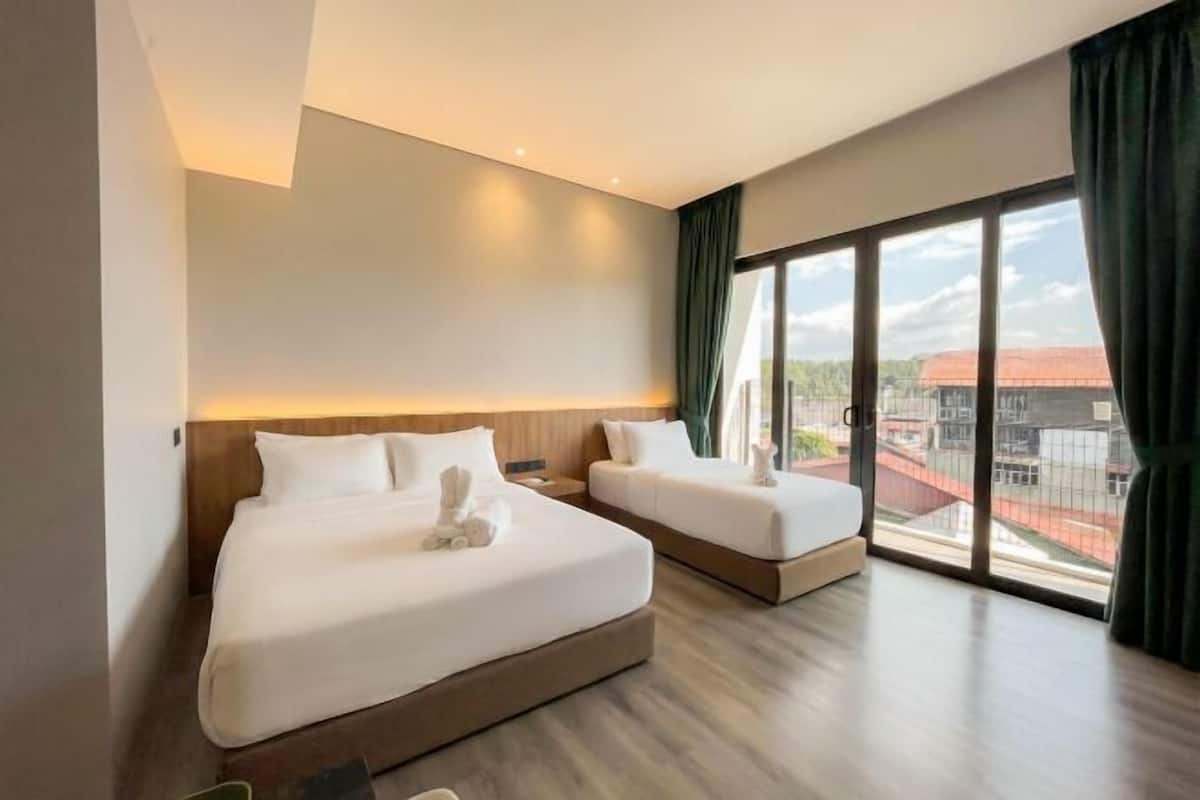 A hotel room with two beds, large windows, and a view of buildings.