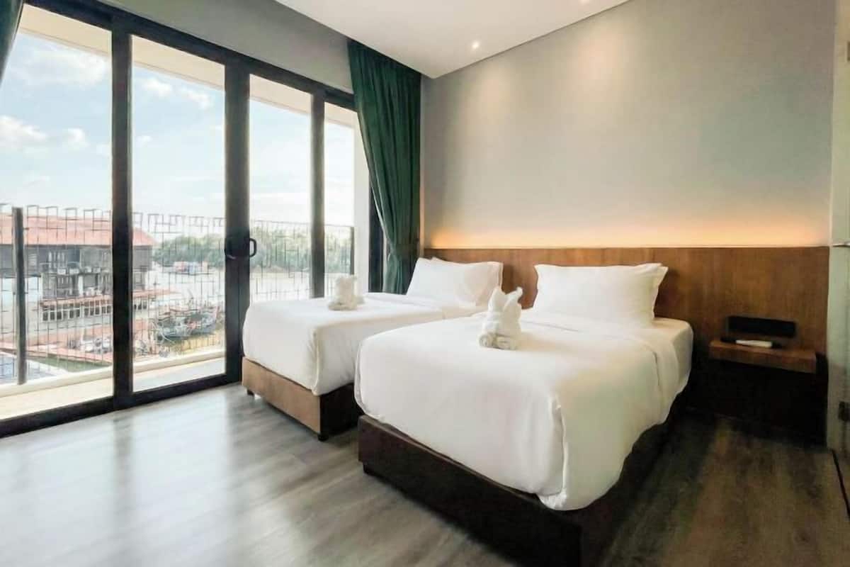A hotel room with two beds, a large window with a view of the city, and a wooden headboard.
