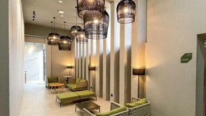 A modern lobby with a seating area featuring green upholstered sofas and chairs, a coffee table, and pendant lighting. - Crosview (Kuala Sepetang)