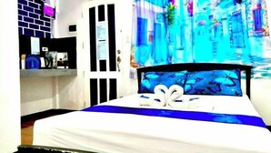 A hotel room with a bed, a wall-mounted TV, a door, and a curtain with a blue and white pattern. - DMI Hotels and Apartments with Newly opened Lava Stone Pool by Reddoorz (Tabaco)