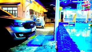 A vehicle parked in a garage with a visible door and a small building in the background. - DMI Hotels and Apartments with Newly opened Lava Stone Pool by Reddoorz (Tabaco)