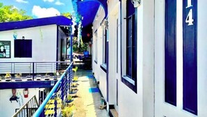 A corridor with a blue railing, potted plants, and a door marked with the number 14. - DMI Hotels and Apartments with Newly opened Lava Stone Pool by Reddoorz (Tabaco)