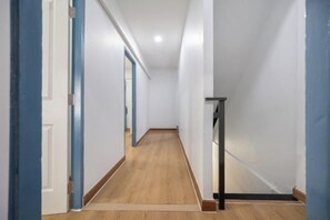 A hallway with white walls, wooden flooring, and blue door frames. - Spacious Family Haven Chatuchak Market - 5BR House (Bangkok)